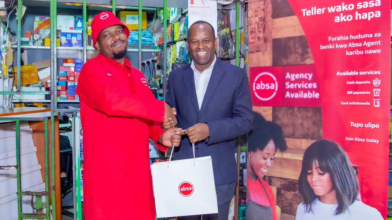 Absa Bank Kenya MD and CEO Abdi Mohamed presents a gift to Absa Bank Ruaka agent Sammy Njoroge during the launch of Absa Bank agency banking expansion drive. PHOTO/COURTESY